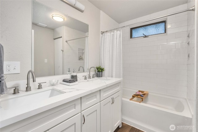 bathroom featuring double vanity, shower / bathtub combination with curtain, a sink, and wood finished floors