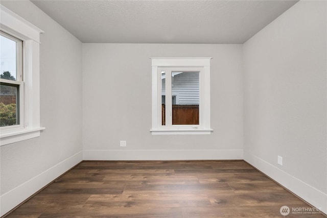 unfurnished room with dark wood finished floors, a textured ceiling, and baseboards