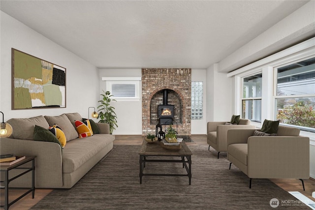 living area featuring dark wood-type flooring, a wood stove, and a textured ceiling