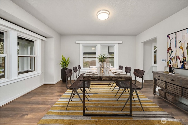 dining room featuring a textured ceiling, dark wood finished floors, and baseboards