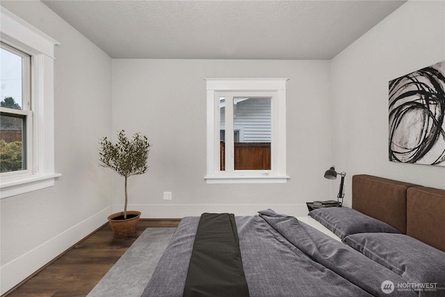 bedroom with dark wood finished floors, a textured ceiling, and baseboards