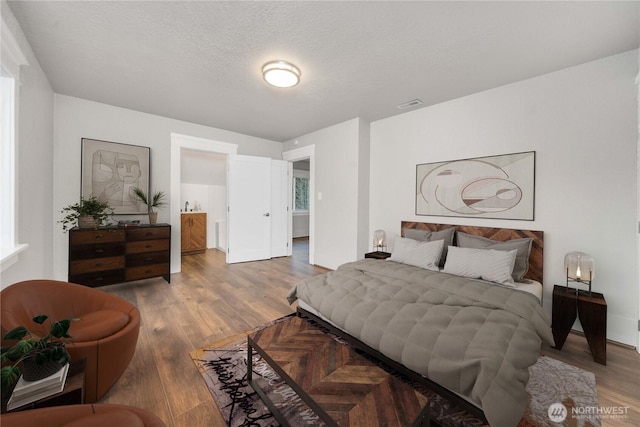 bedroom featuring a textured ceiling, wood finished floors, and visible vents