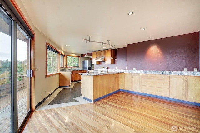 kitchen featuring under cabinet range hood, a peninsula, a sink, light wood-type flooring, and stainless steel fridge with ice dispenser