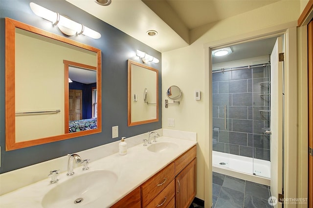 bathroom with double vanity, a sink, and tiled shower