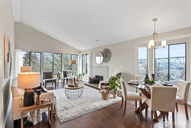 living room with a brick fireplace, a healthy amount of sunlight, an inviting chandelier, and wood finished floors