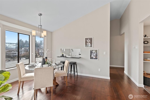 dining area with dark wood-style floors, lofted ceiling, baseboards, and an inviting chandelier