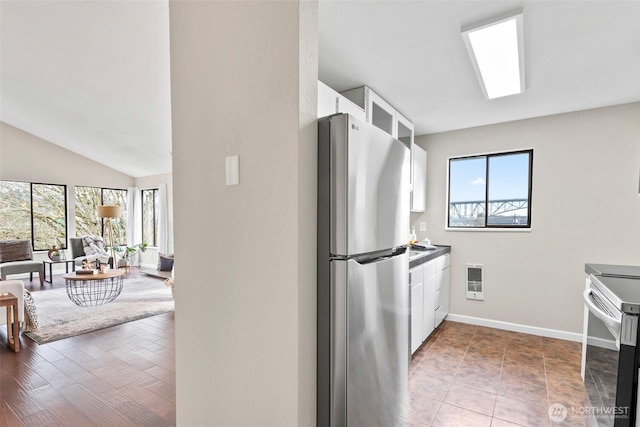 kitchen with baseboards, white cabinets, dark countertops, appliances with stainless steel finishes, and glass insert cabinets