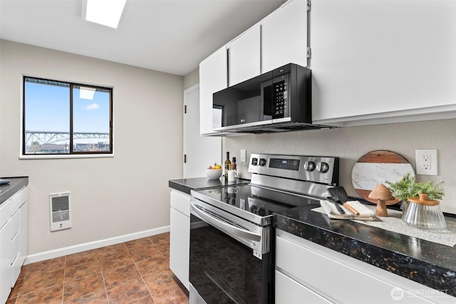 kitchen featuring black microwave, white cabinets, baseboards, and stainless steel electric range