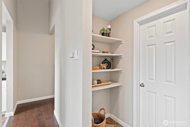 corridor with dark wood finished floors and baseboards