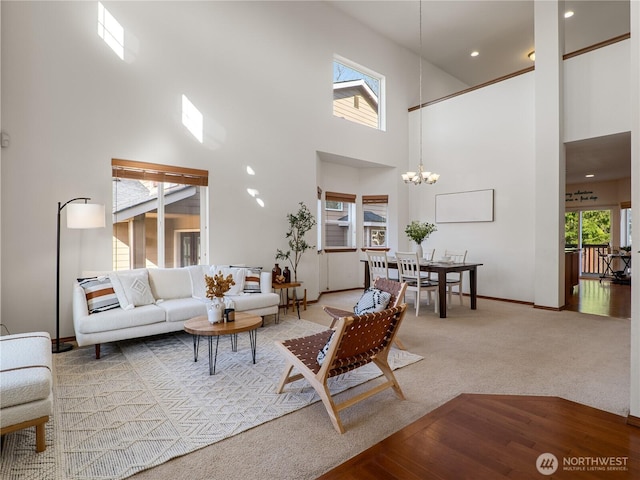 living area with baseboards, carpet floors, a towering ceiling, and a notable chandelier