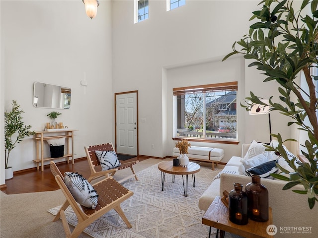 living area featuring a towering ceiling, baseboards, and wood finished floors