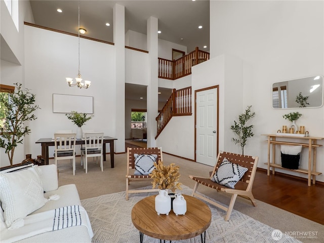 living area with a towering ceiling, stairway, wood finished floors, an inviting chandelier, and recessed lighting