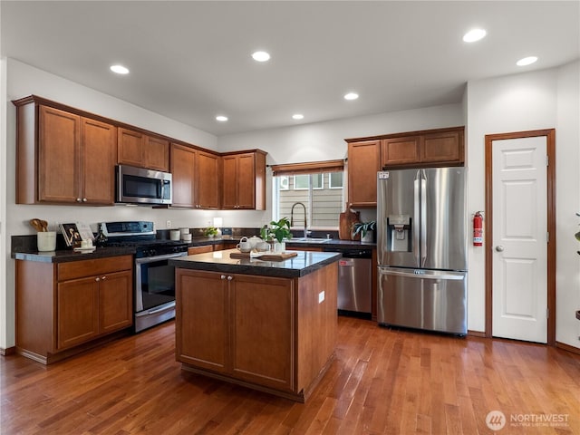 kitchen with recessed lighting, dark wood-type flooring, a kitchen island, appliances with stainless steel finishes, and dark countertops