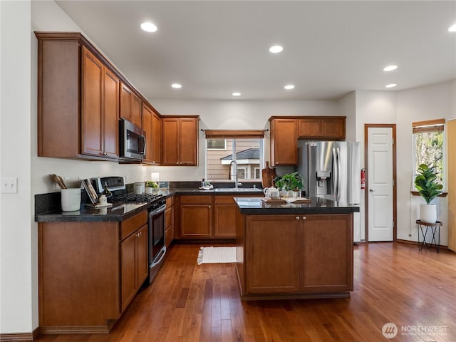 kitchen featuring recessed lighting, a kitchen island, a sink, appliances with stainless steel finishes, and dark wood-style floors