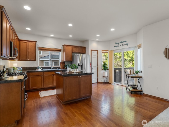 kitchen featuring stainless steel appliances, dark countertops, dark wood-type flooring, a sink, and a kitchen island