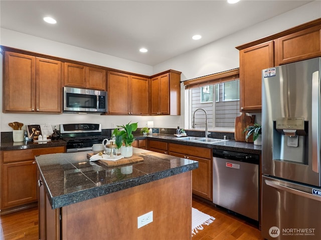 kitchen featuring appliances with stainless steel finishes, brown cabinets, a sink, and wood finished floors