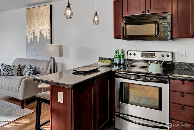 kitchen with black microwave, stainless steel electric stove, a peninsula, wood finished floors, and hanging light fixtures