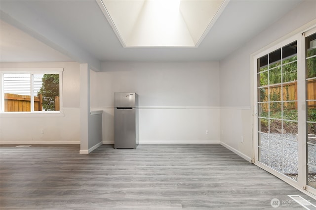 unfurnished room featuring a skylight, baseboards, and wood finished floors