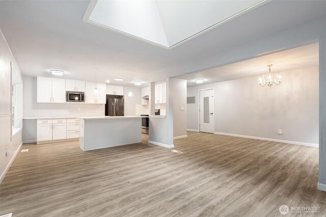 kitchen with white cabinets, light wood finished floors, stainless steel appliances, and open floor plan