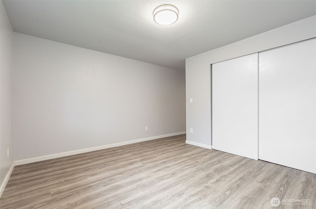 unfurnished bedroom featuring a closet, light wood-style flooring, and baseboards