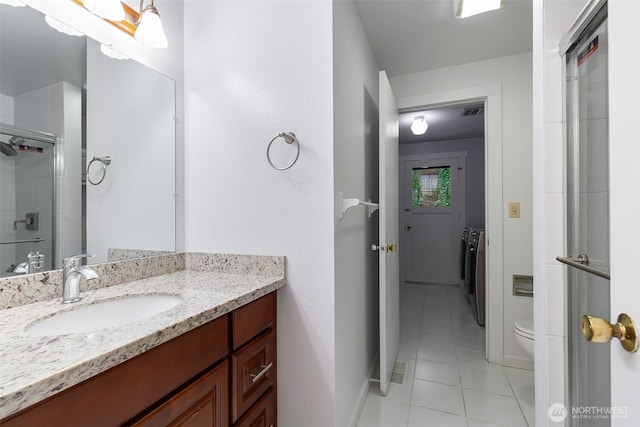 full bathroom featuring washer / clothes dryer, toilet, a stall shower, vanity, and tile patterned flooring