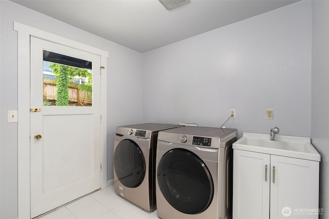 washroom with cabinet space, visible vents, light tile patterned flooring, a sink, and washer and dryer