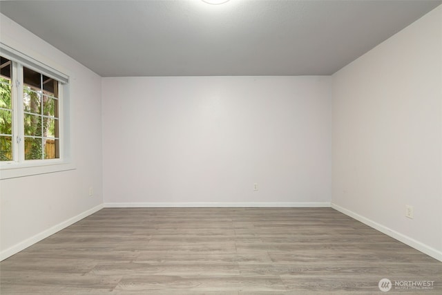 spare room featuring light wood-style floors and baseboards