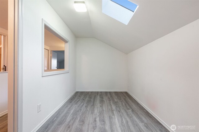 bonus room with lofted ceiling with skylight, wood finished floors, and baseboards