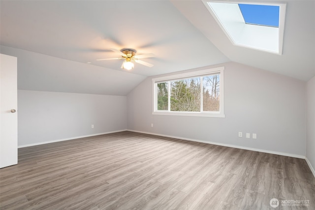 bonus room featuring lofted ceiling with skylight, baseboards, and wood finished floors