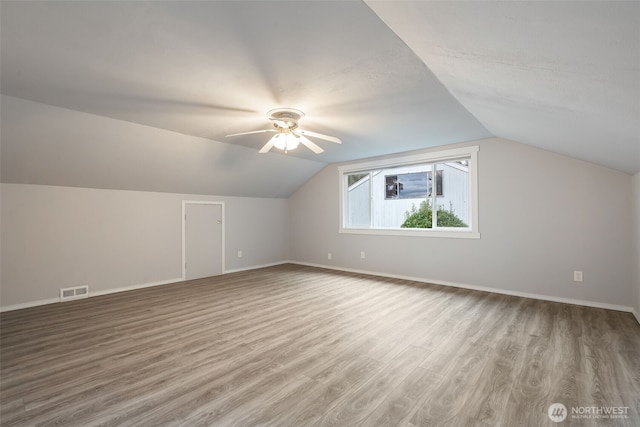 bonus room featuring lofted ceiling, wood finished floors, visible vents, and baseboards