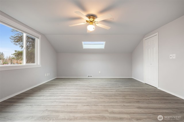 bonus room with lofted ceiling with skylight, light wood-type flooring, and visible vents