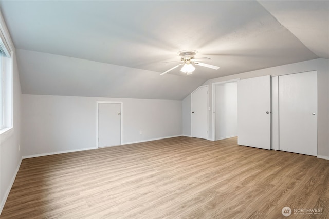 additional living space with lofted ceiling, light wood-type flooring, a ceiling fan, and baseboards