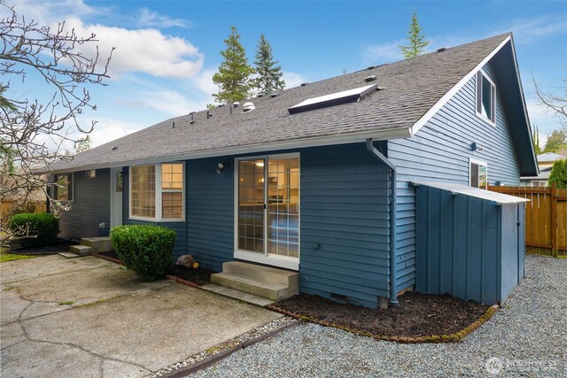 back of property with entry steps, a shingled roof, crawl space, and fence