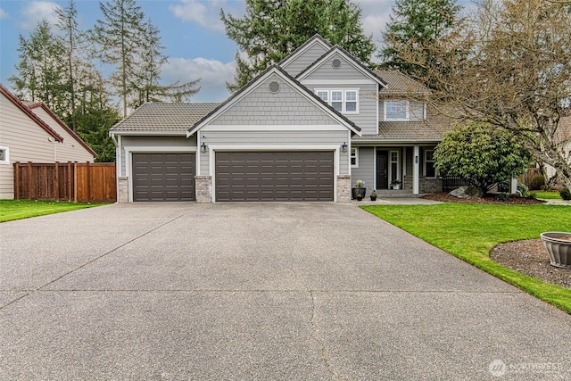 craftsman-style home with a front lawn, concrete driveway, fence, and a garage