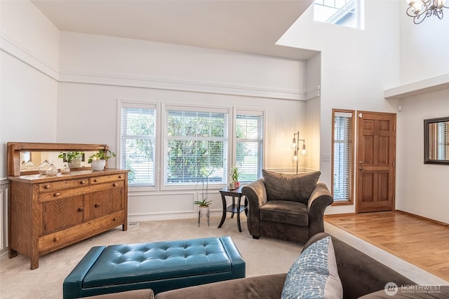 living room featuring an inviting chandelier, baseboards, a towering ceiling, and wood finished floors