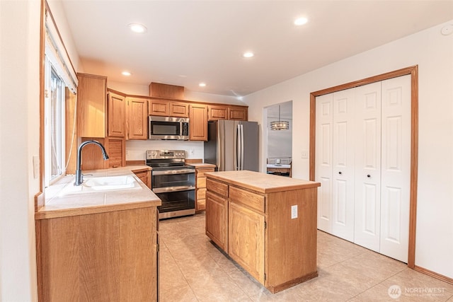 kitchen featuring a kitchen island, stainless steel appliances, light countertops, and a sink