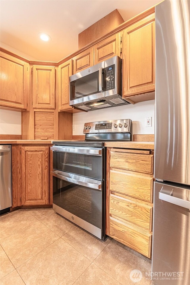 kitchen with recessed lighting, appliances with stainless steel finishes, light tile patterned flooring, and light countertops