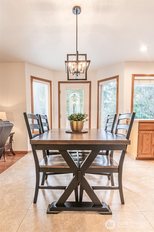 dining space with a wealth of natural light, light tile patterned floors, baseboards, and an inviting chandelier