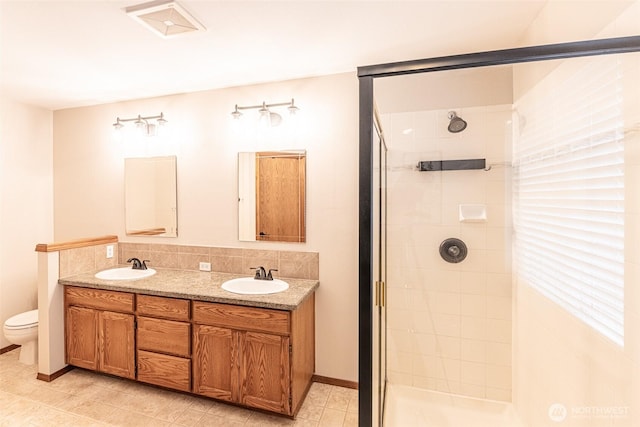 full bath with double vanity, toilet, a stall shower, and a sink