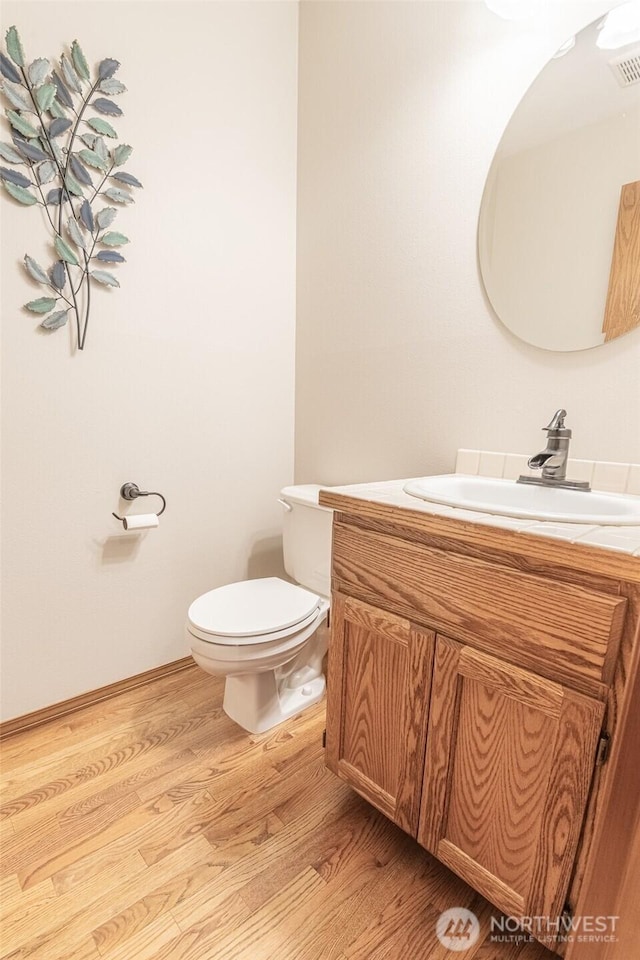 bathroom featuring visible vents, toilet, wood finished floors, and vanity