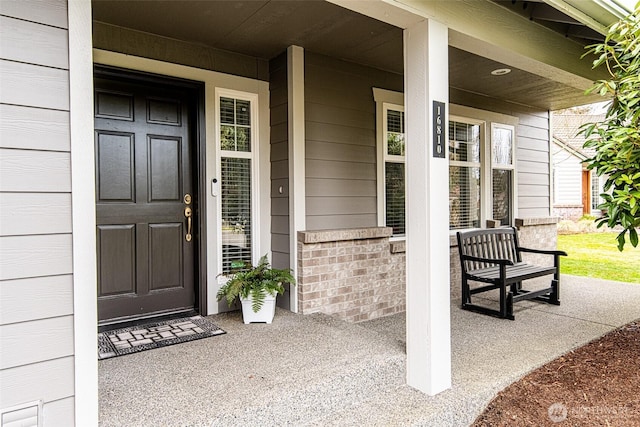 property entrance featuring brick siding and covered porch