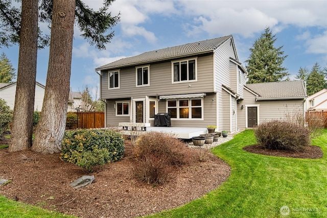 rear view of property with a yard, a patio, and fence