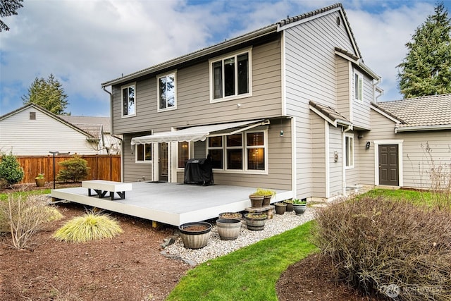 back of property featuring a deck and fence