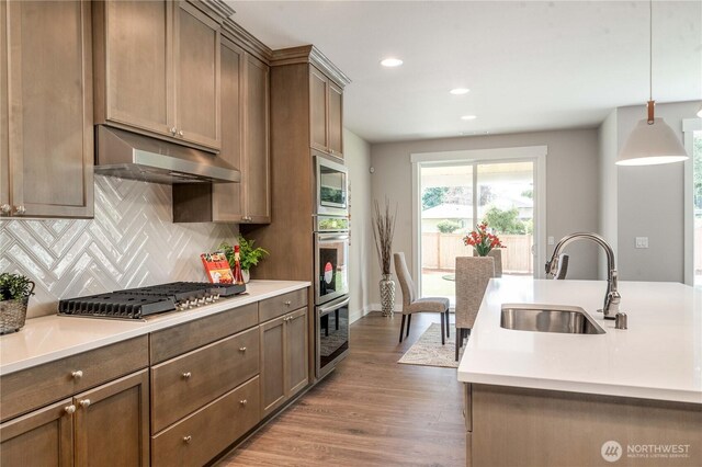 15814 Boise Ln SE, Yelm, WA 98597 - kitchen with under cabinet range hood, pendant lighting, light countertops, and a sink
