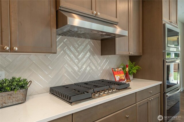 15814 Boise Ln SE, Yelm, WA 98597 - kitchen featuring range hood, appliances with stainless steel finishes, light countertops, and decorative backsplash