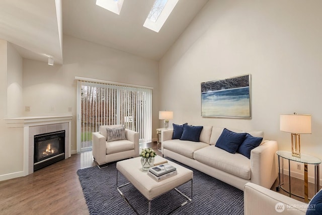 living room with high vaulted ceiling, baseboards, a tiled fireplace, and wood finished floors