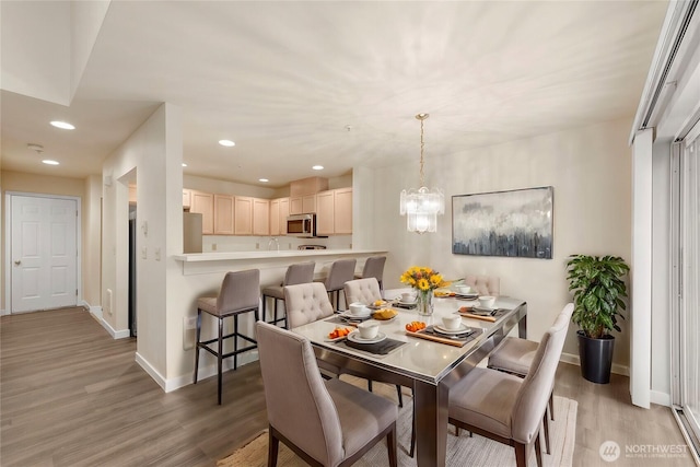 dining area with light wood-type flooring, an inviting chandelier, baseboards, and recessed lighting