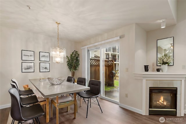 dining space with baseboards, wood finished floors, and a tile fireplace