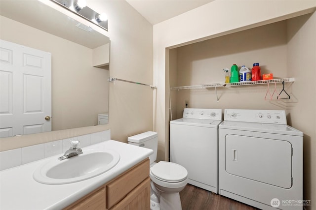 half bathroom featuring vanity, wood finished floors, toilet, and washer and dryer