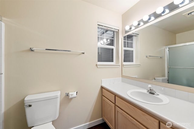 bathroom featuring a shower with door, visible vents, toilet, vanity, and baseboards